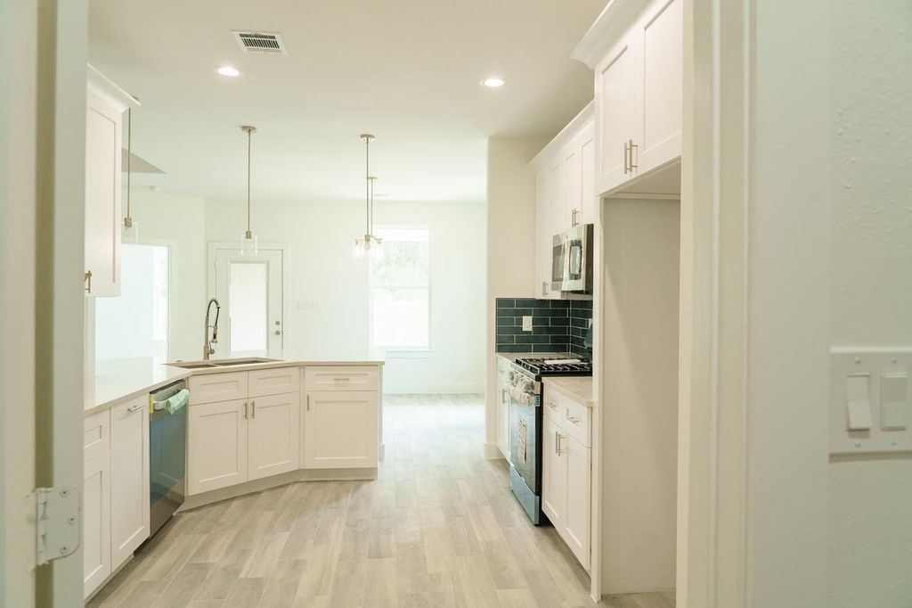 Kitchen with white cabinets, an island and pendant lights
