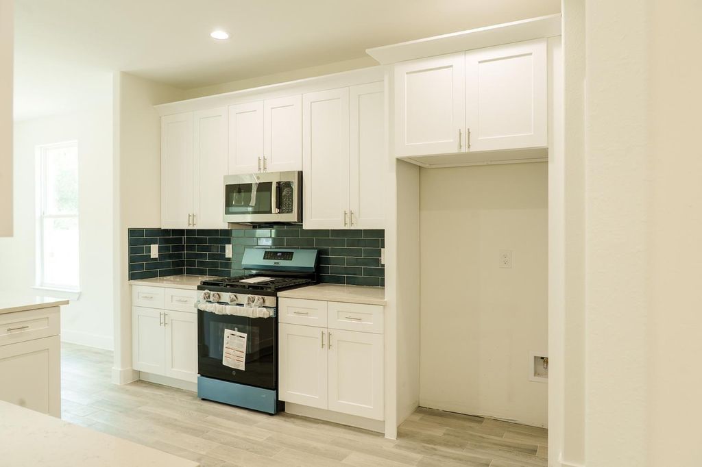 Kitchen with a gas range, a dark tile backsplash and a built-in microwave
